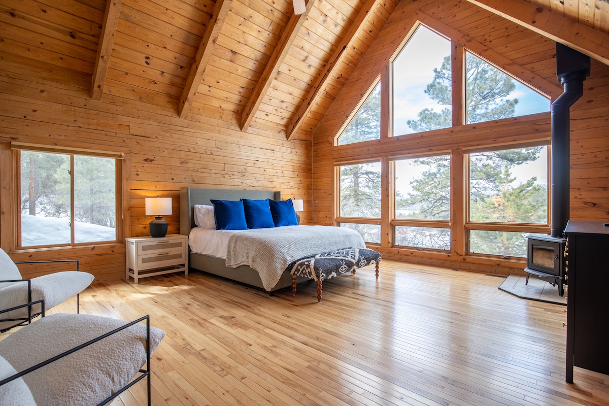 King suite with vaulted ceiling, wood-burning stove, and picture windows at Wildcat Cabin