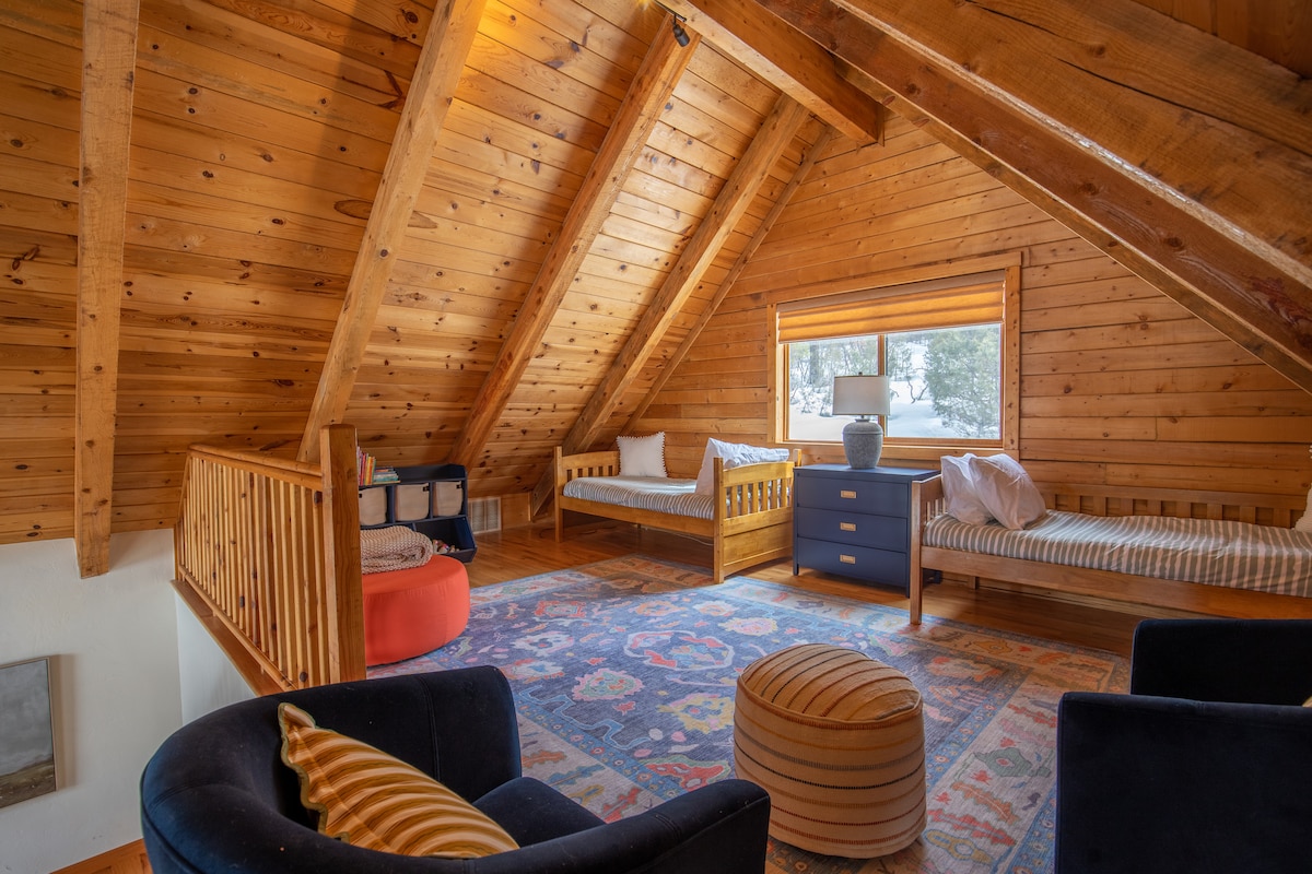 Loft with twin beds, exposed beams, and cozy rugs at Wildcat Cabin