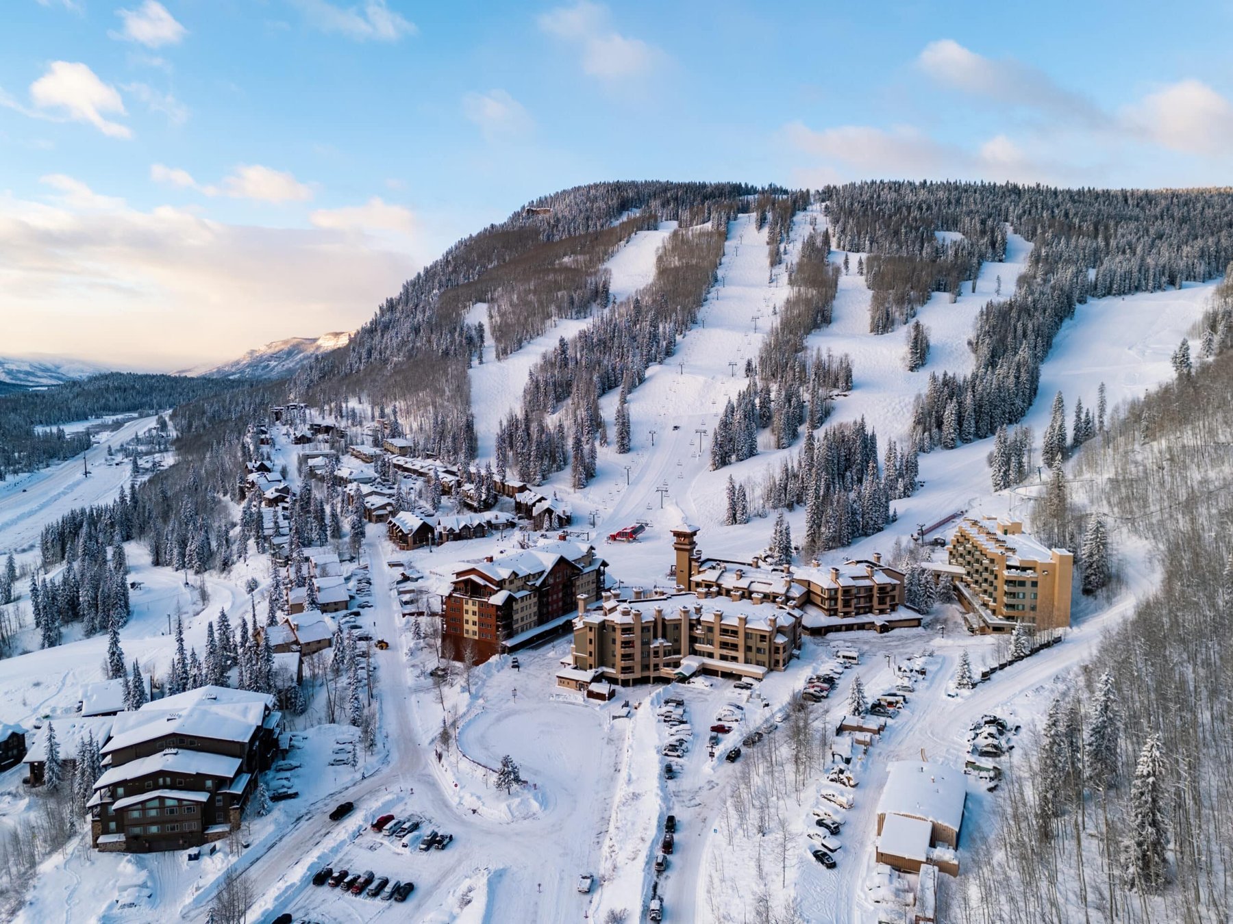 Aerial drone view of Purgatory Resort base village in winter with snow-covered ski runs behind